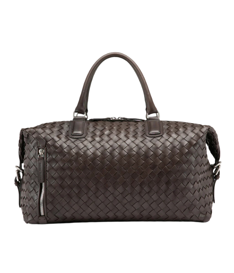 Handwoven brown leather Armor 019 Travel Bag with durable handles, an adjustable shoulder strap, side buckles, and a spacious interior with a side zipper pocket. Made in Italy.