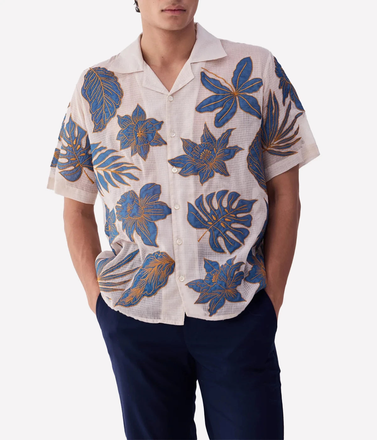 Perte D’ego Blue Floral Appliqué Shirt made from sheer, lightweight cotton mesh, featuring hand-embroidered floral appliqué detailing on the front. Relaxed fit, short sleeves, and a breezy design, perfect for beachside styling or warm-weather occasions.