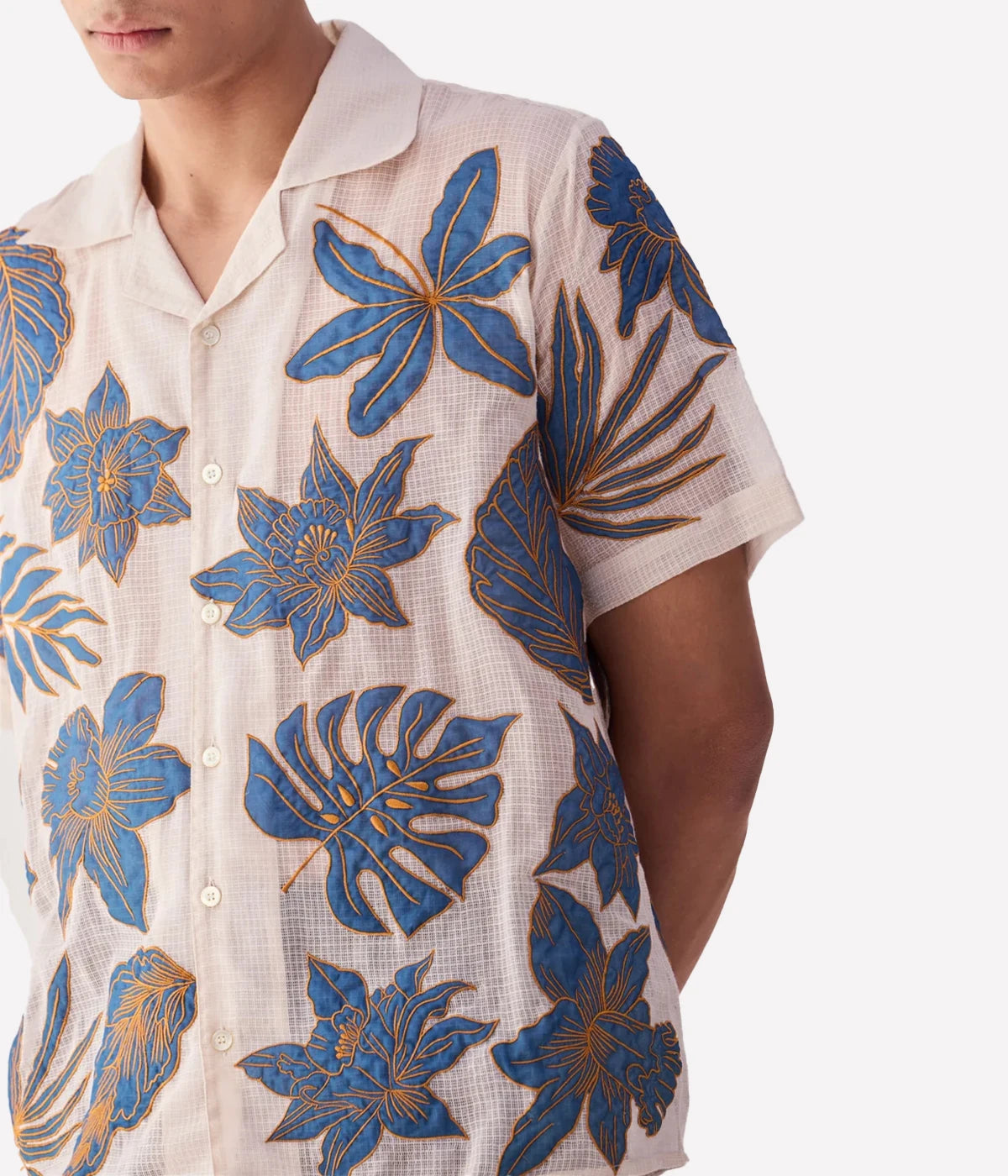 Perte D’ego Blue Floral Appliqué Shirt made from sheer, lightweight cotton mesh, featuring hand-embroidered floral appliqué detailing on the front. Relaxed fit, short sleeves, and a breezy design, perfect for beachside styling or warm-weather occasions.