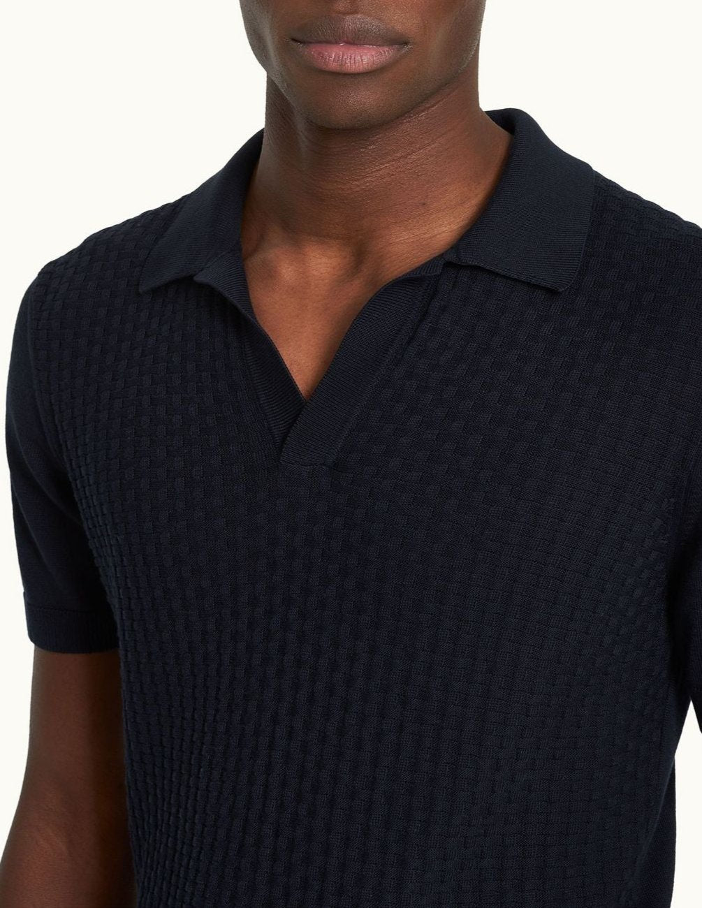 Silk-cotton blend resort-style knit with a tailored fit, featuring a short, open placket, ribbed cuffs, hem, and placket. Jacquard knit pattern with fully fashioned construction and O.B. stitch near the hem