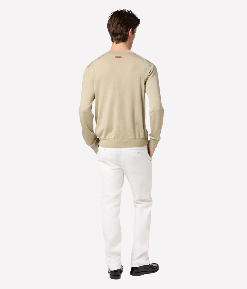 White slim-fit chino pants with a low waist, made from soft stretch cotton with an enzyme-washed, optical bleached finish. Features a white suede back patch with a gunmetal-finish logo and a gold-tone button. Made in Italy.