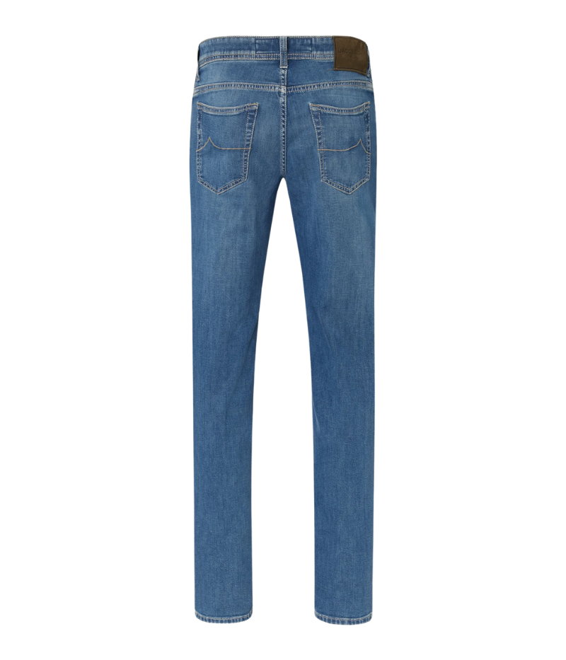 Nick 5-Pocket Jeans in medium blue stonewashed denim, showcasing their slim fit and low waist. The jeans have a lived-in feel with subtle whiskering and abrasions. Details include an olive green nubuck back patch with an engraved logo, embroidered branding, and a signature Jacob Cohën fragrance. Made in Italy from a soft stretch cotton blend.