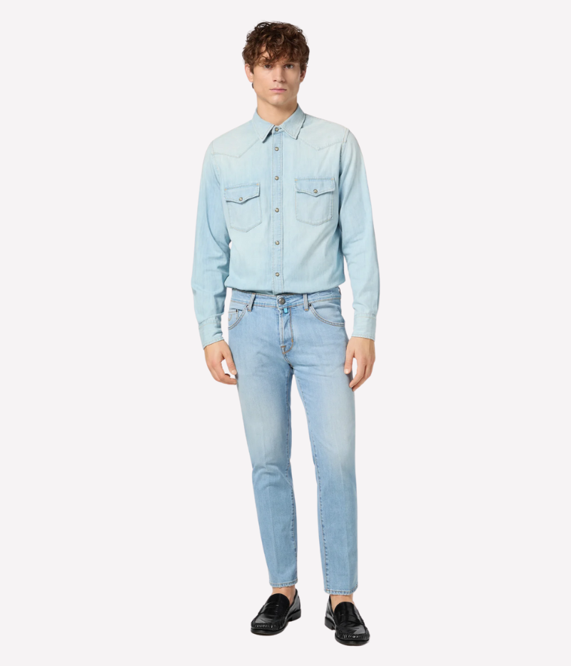 Light blue cropped carrot-leg jeans with a slim fit and low crotch. Made from soft, bleach-washed comfort denim with whiskering and distressed details. Features a beige nubuck back patch and vintage silver-tone button. Made in Italy.