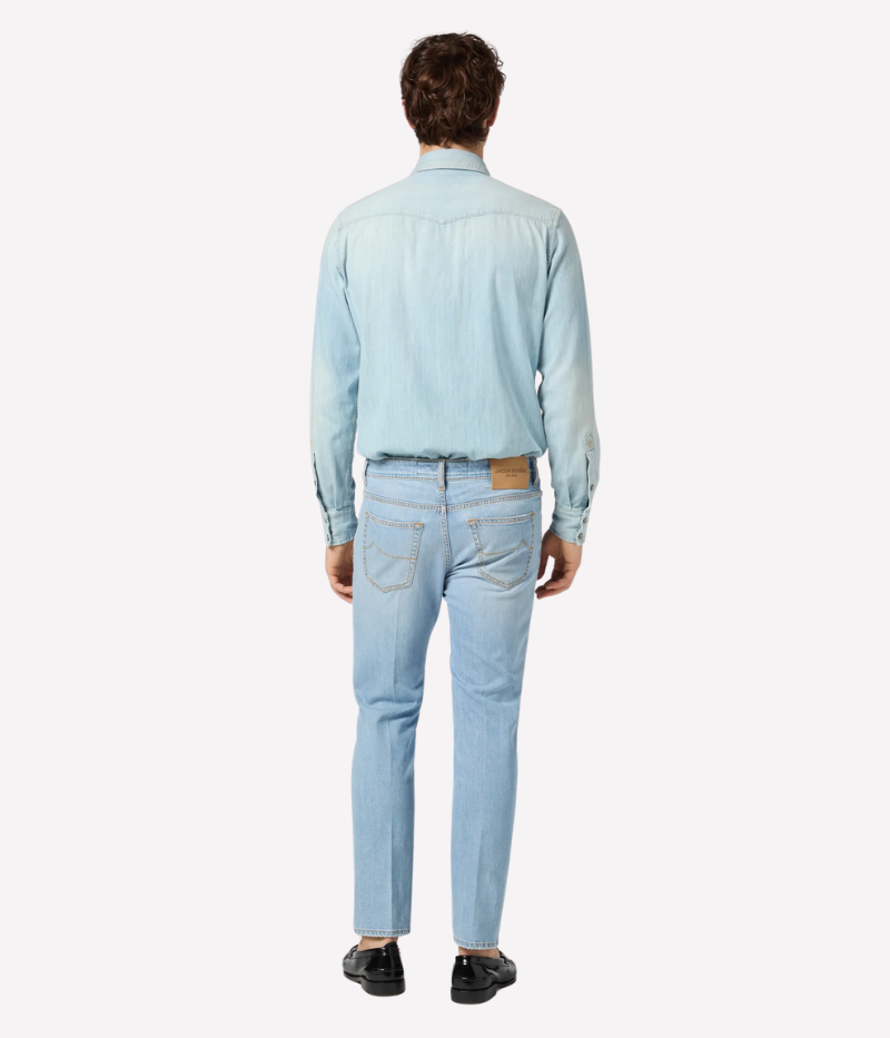 Light blue cropped carrot-leg jeans with a slim fit and low crotch. Made from soft, bleach-washed comfort denim with whiskering and distressed details. Features a beige nubuck back patch and vintage silver-tone button. Made in Italy.