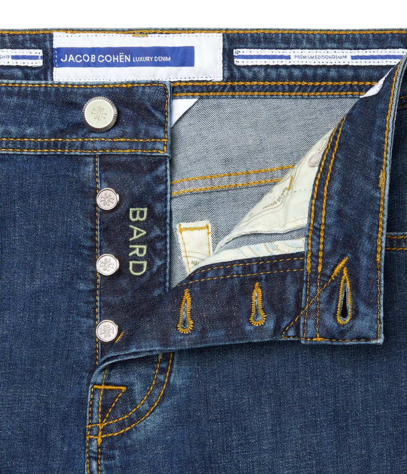 Close-up of the Bard 5-Pocket Jeans in dark blue stonewashed stretch denim, featuring a regular-slim fit. Crafted from a cotton-linen blend for comfort and durability, these jeans include an embroidered logo on the fifth pocket, a World print bandana, and a spool of thread. Finished with Jacob Cohën’s signature fragrance. Made in Italy.