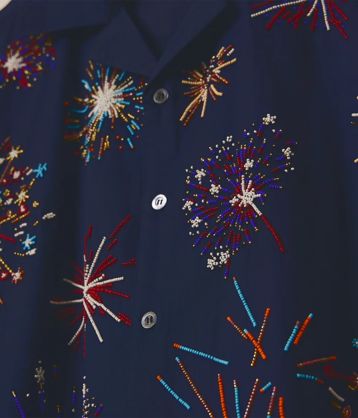 Perte D’ego 'Le Celebration' Fireworks Embroidered Shirt in rich navy cotton, featuring a relaxed fit, Cuban collar, and intricate hand-embroidered beadwork resembling fireworks. Finished with Mother of Pearl buttons for a statement, head-turning look.