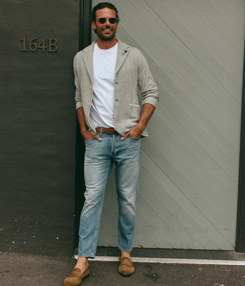 Male model wearing light blue tapered Lardini jeans styled with a smart casual outfit; jeans feature a classic five-pocket design, subtle whiskering, and a sharp tapered fit, blending relaxed comfort with refined Italian craftsmanship.