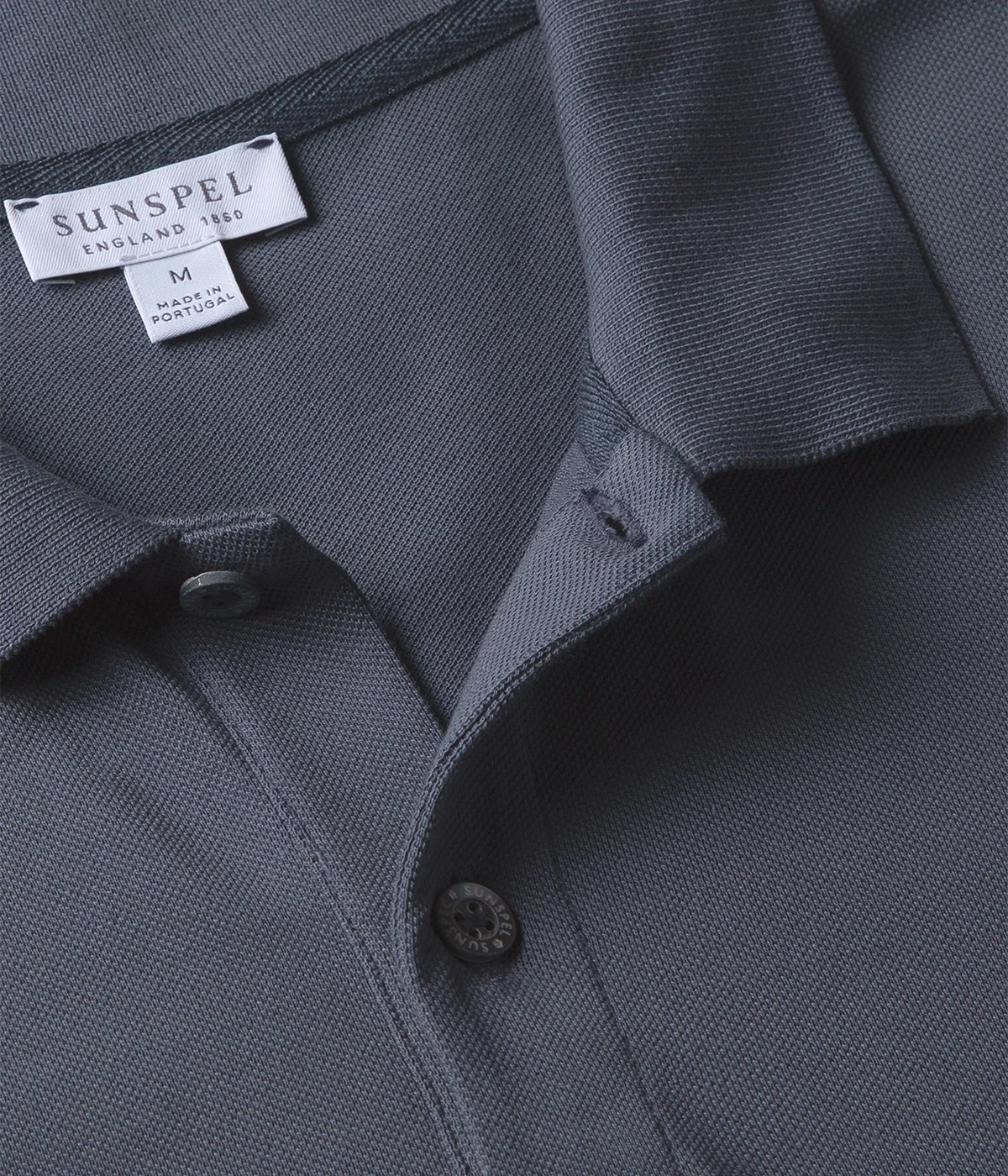 Slate blue piqué polo shirt for men made from Supima cotton. Features ribbed collar, side vents, and branded shell buttons for a polished look.