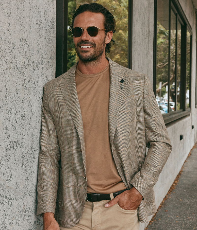 Beige Lardini silk jacket featuring a subtle check pattern, two-button closure, notch lapels with the signature Lardini floral pin, patch pockets, and soft tailoring for a lightweight, relaxed fit.