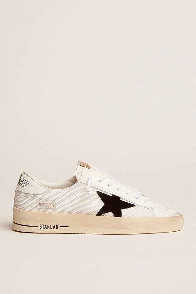 The Golden Goose Stardan Sneaker in White and Black features a sleek netted upper with shiny leather toe and heel details, combining sporty style with luxury craftsmanship. The iconic suede star and durable rubber sole offer comfort and timeless appeal, perfect for both casual and elevated looks.