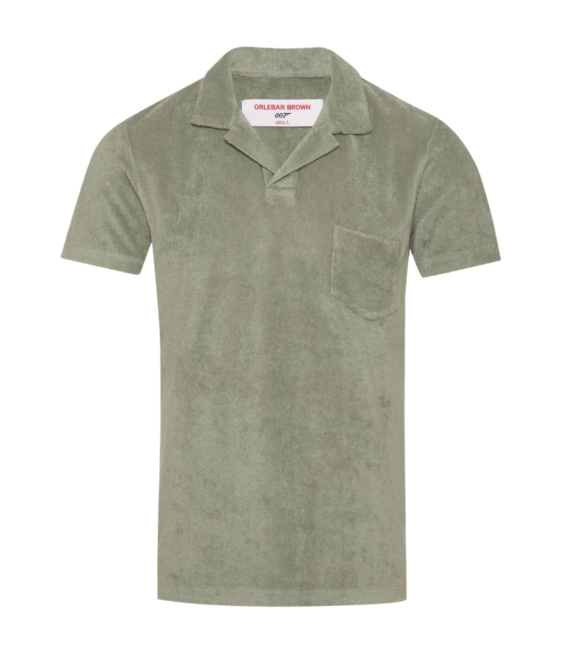 Orlebar Brown Terry Towelling Polo in Penny Green, inspired by The Man with the Golden Gun. Made from soft terry towelling cotton, this vintage-style polo features a tailored fit, straight-cut silhouette, and a buttonless placket for a refined, effortless look. Perfect for both casual and dressed-up occasions, this piece offers the ideal balance of sophistication and comfort.